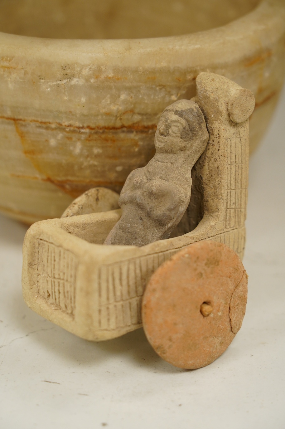 An alabaster mortar, possibly Ancient Egyptian, 17cm diameter, the handles ground off and a terracotta figure with chariot, possibly Mesopotamian. Condition - fair, restoration to chariot